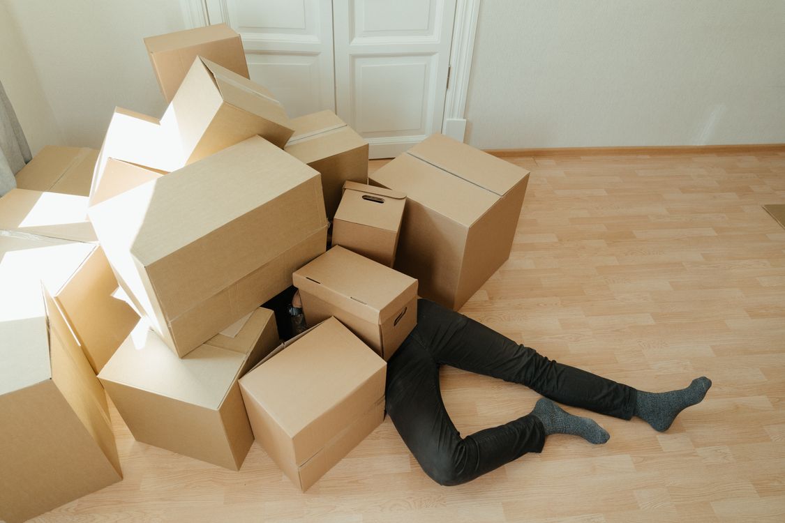 Cajas de carton marrones apiladas en piso de madera durante mudanza