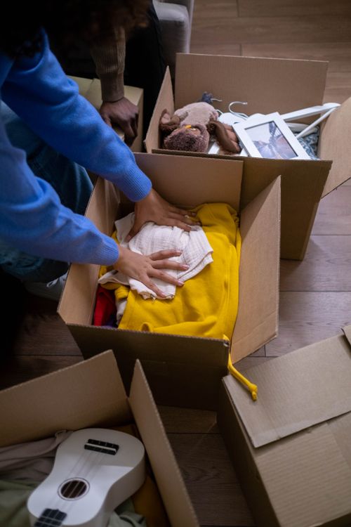 Persona embalando ropa con cuidado en una caja de cartón para la mudanza