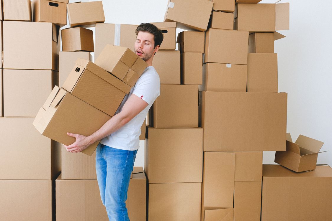 Hombre joven cargando varias cajas de cartón durante una mudanza a un nuevo departamento
