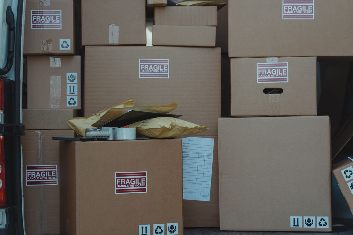 Cajas de cartón etiquetadas como frágil apiladas dentro de un vehículo de mudanza