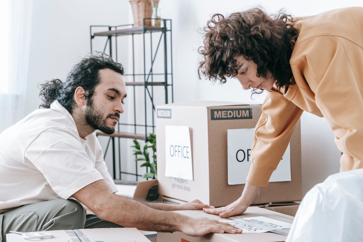 Pareja etiquetando cajas de cartón durante una mudanza